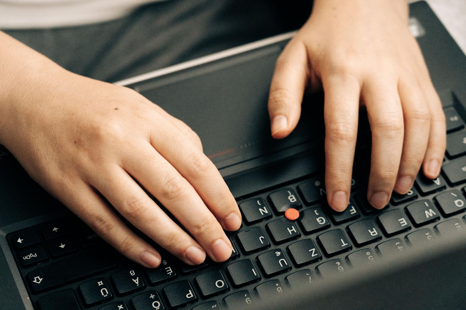 Manos escribiendo en el teclado de un portátil para ejecutar comandos en el CMD