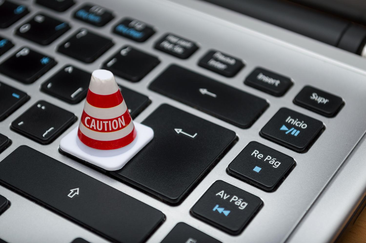 Miniatura de un cono de precaución sobre un teclado de computadora, representando restricciones de permisos y bloqueos del sistema.