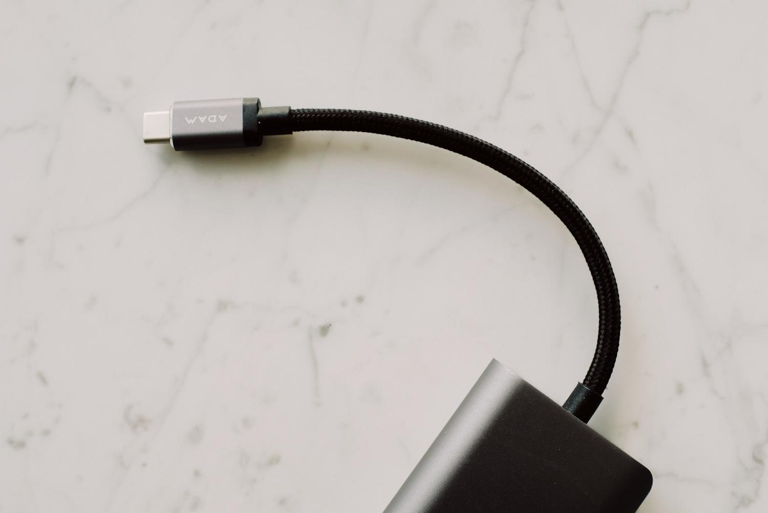 Primer plano detallado de un cable USB-C negro sobre una superficie clara, representando la conexión del móvil al PC.