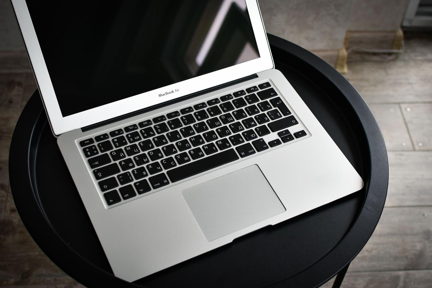 Vista elegante de un MacBook sobre una mesa negra en un interior moderno. Vista elegante de un MacBook sobre una mesa negra en un interior moderno.