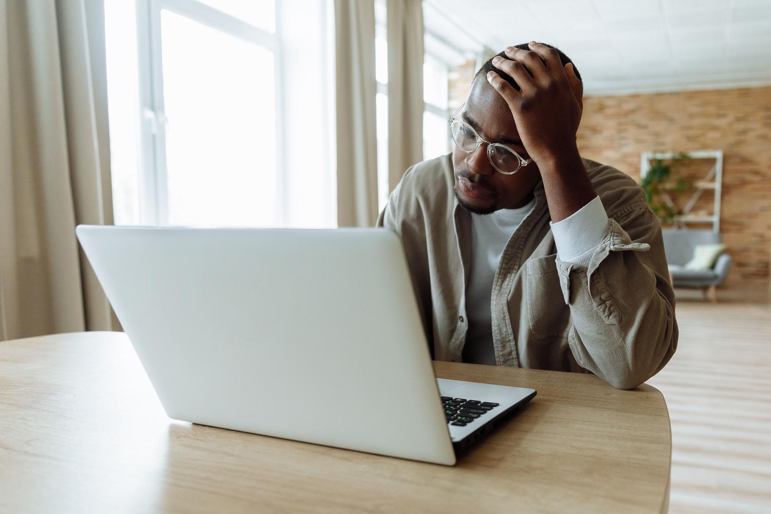 Hombre estresado trabajando con su MacBook, representando la frustración al quedarse sin espacio en el disco.