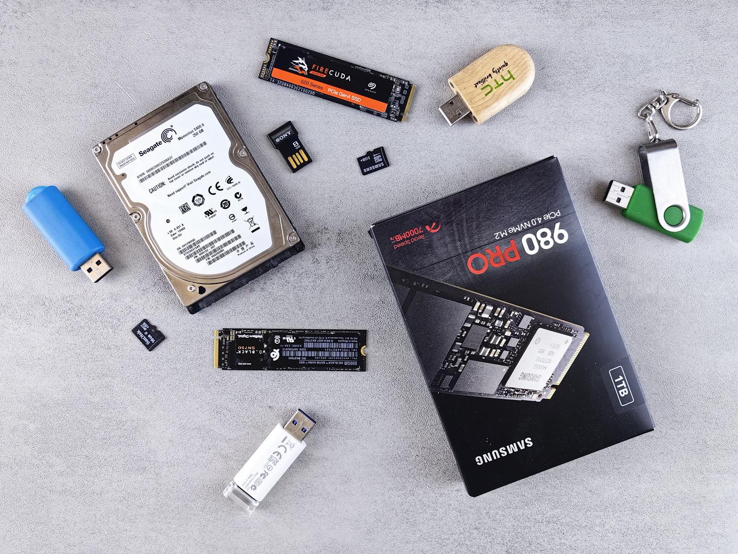 Variedad de dispositivos de almacenamiento como discos duros, SSD y tarjetas SD sobre un fondo gris, ilustrando la recuperación de medios externos. Variedad de dispositivos de almacenamiento como discos duros, SSD y tarjetas SD sobre un fondo gris, ilustrando la recuperación de medios externos.
