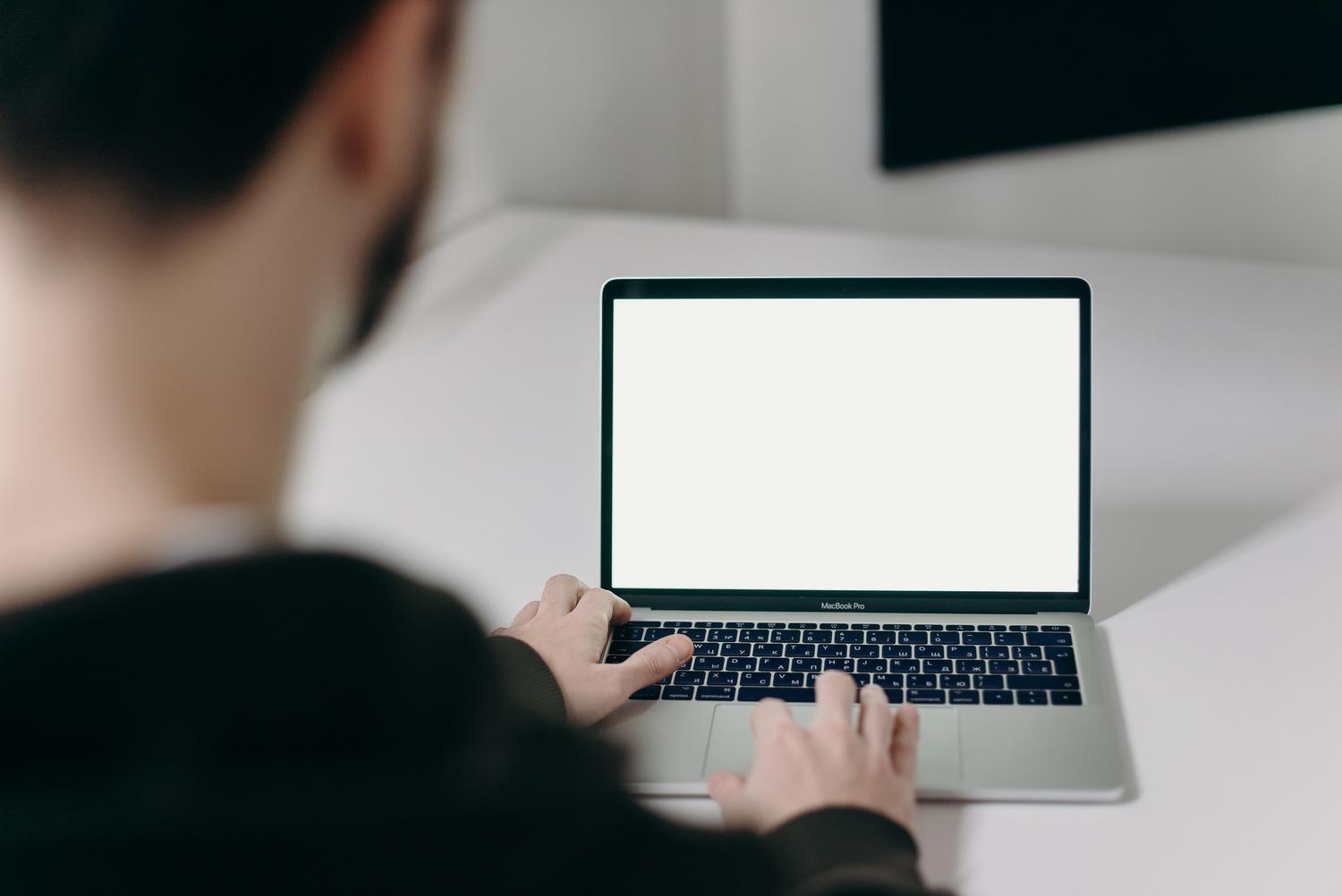 Persona utilizando un MacBook Pro en un espacio de trabajo minimalista y profesional, ideal para ilustrar un tutorial técnico de macOS.