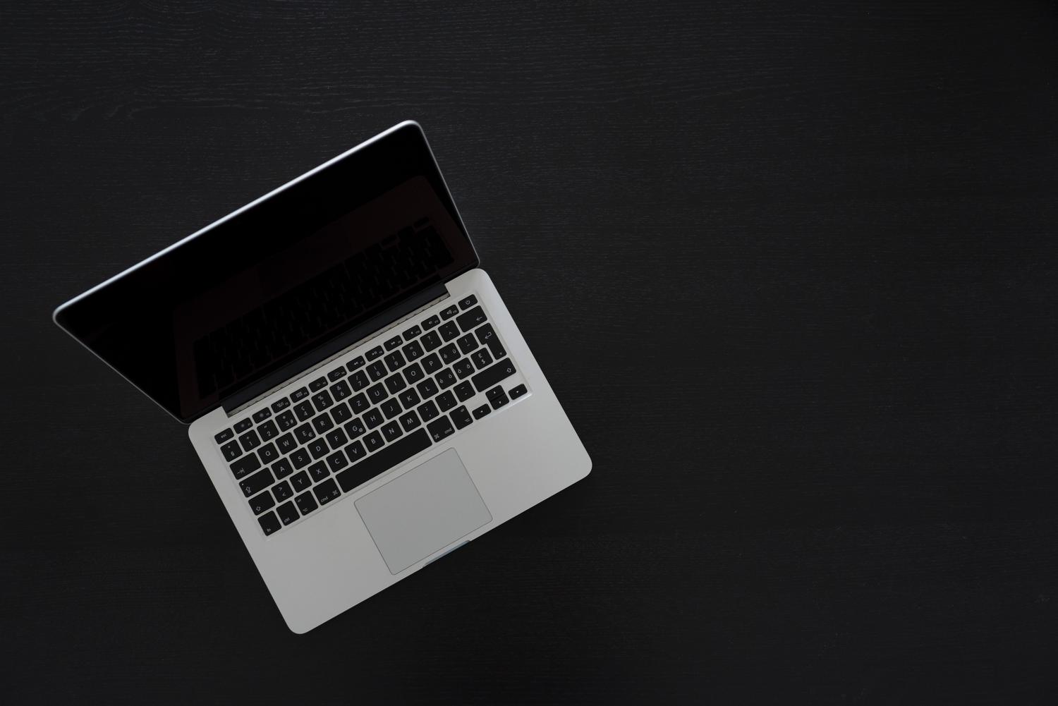 Vista cenital de un MacBook sobre un escritorio oscuro, aportando una estética moderna y minimalista al contenido.
