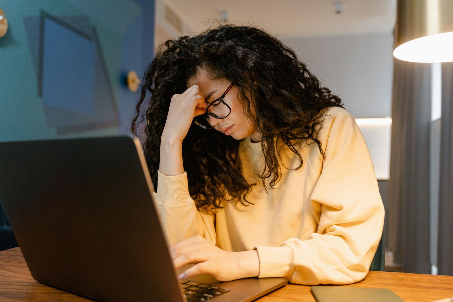 Mujer cansada frente a su computadora, evocando la paciencia y el agotamiento al esperar una actualización de sistema.