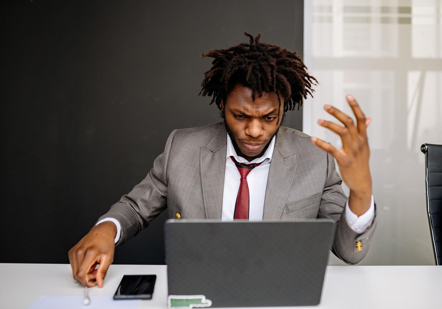 Hombre frustrado por Wi-Fi intermitente Hombre con expresión de frustración mientras trabaja con su portátil, reflejando la desesperación por una conexión Wi-Fi intermitente.