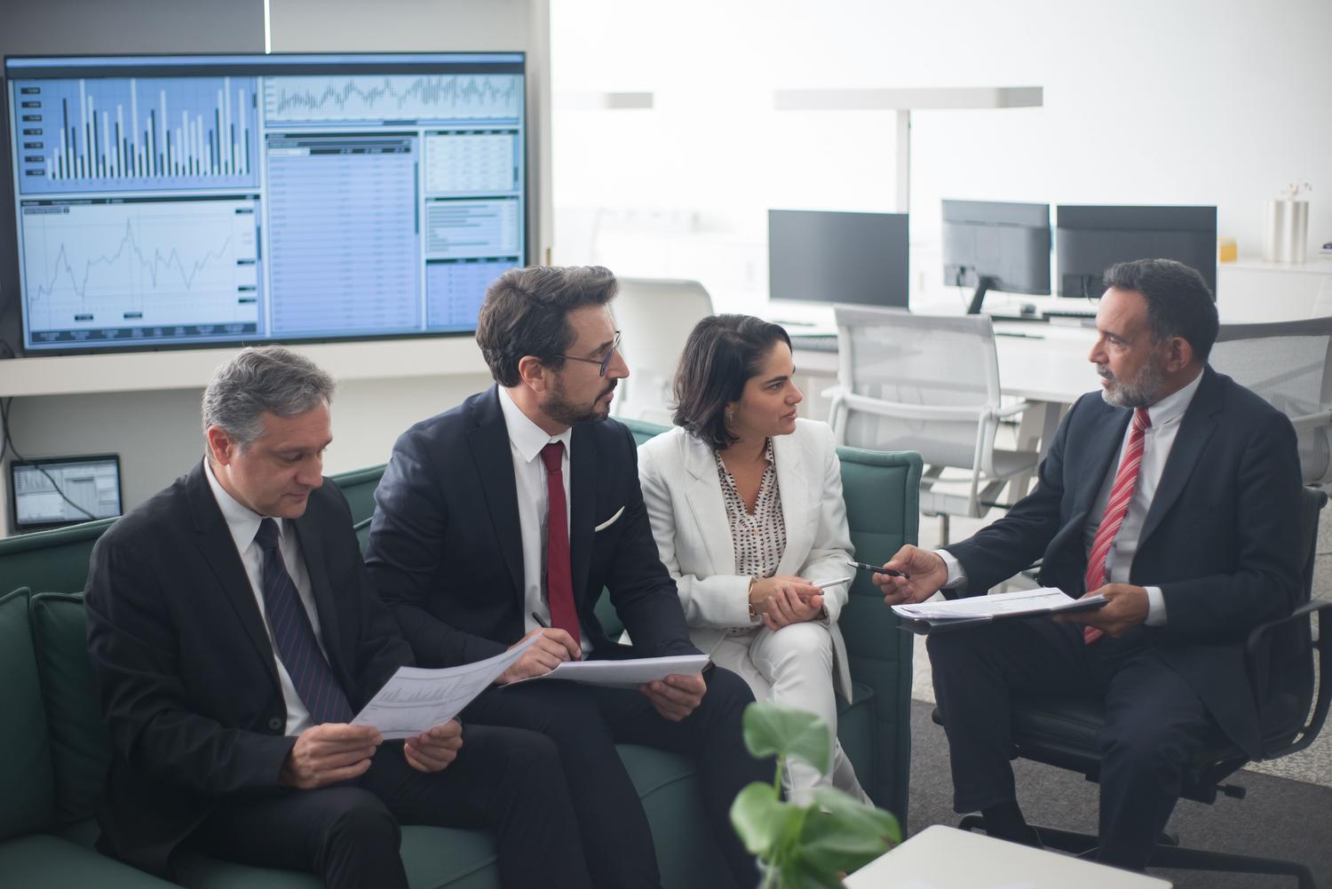 Equipo de trabajo colaborando en el análisis de informes financieros consolidados para la estrategia de Group Reporting.