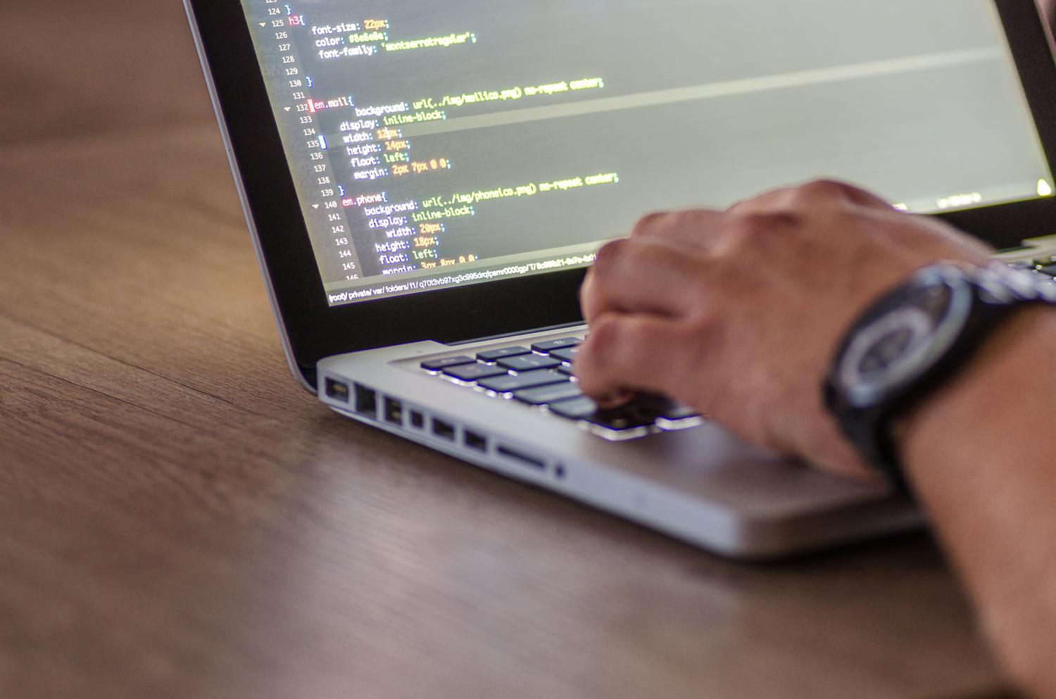 Primer plano de un programador escribiendo código en su portátil, enfocado en el flujo de trabajo.
