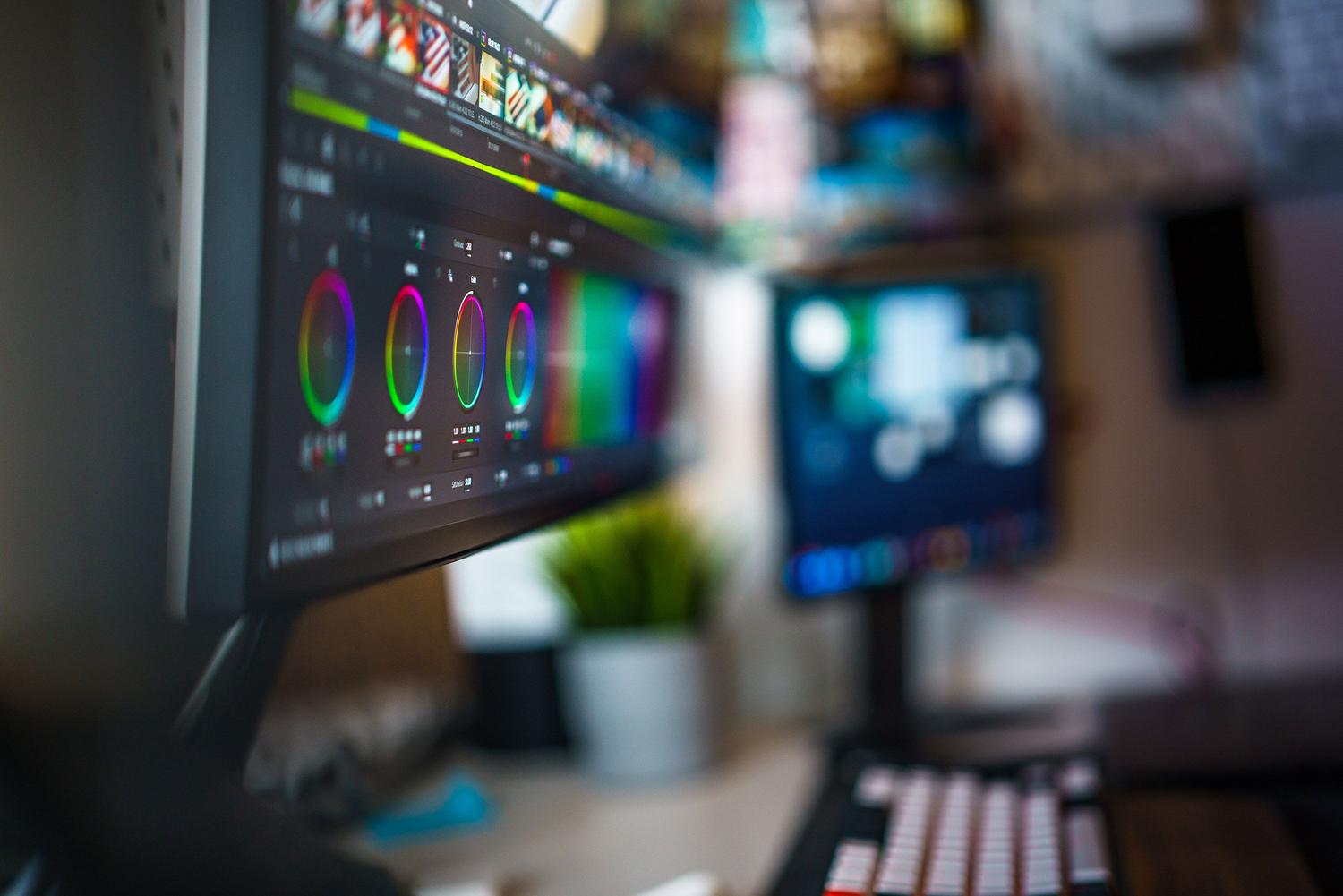 Espacio de trabajo de edición de vídeo con doble monitor mostrando herramientas de corrección de color.