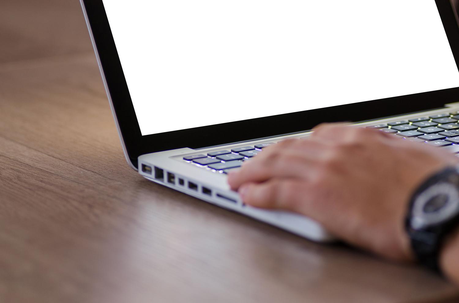 Primer plano de una mano sobre el teclado de un ordenador portátil minimalista