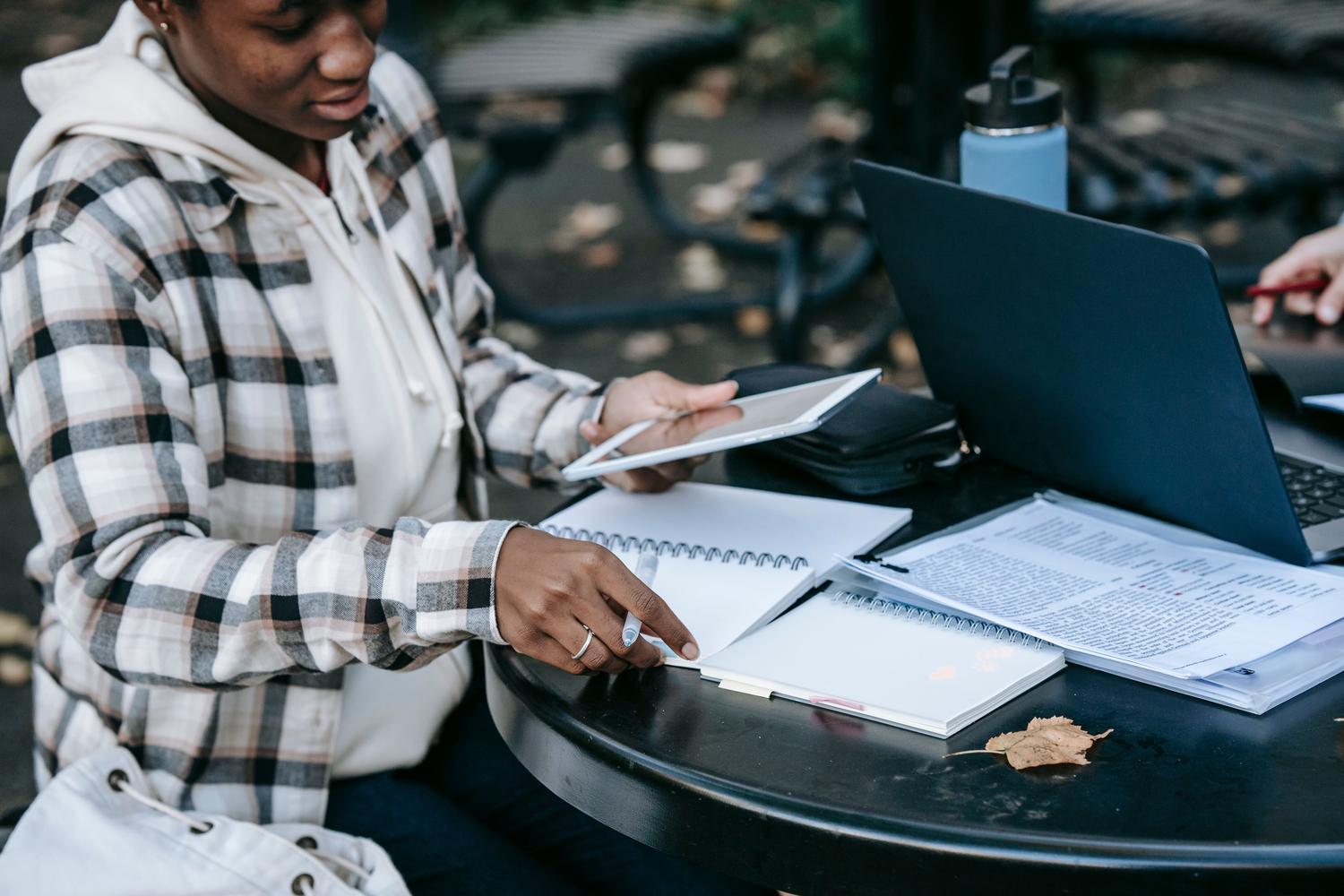 Estudiante tomando notas digitales con lápiz óptico en una tablet al aire libre, destacando la versatilidad de OneNote.