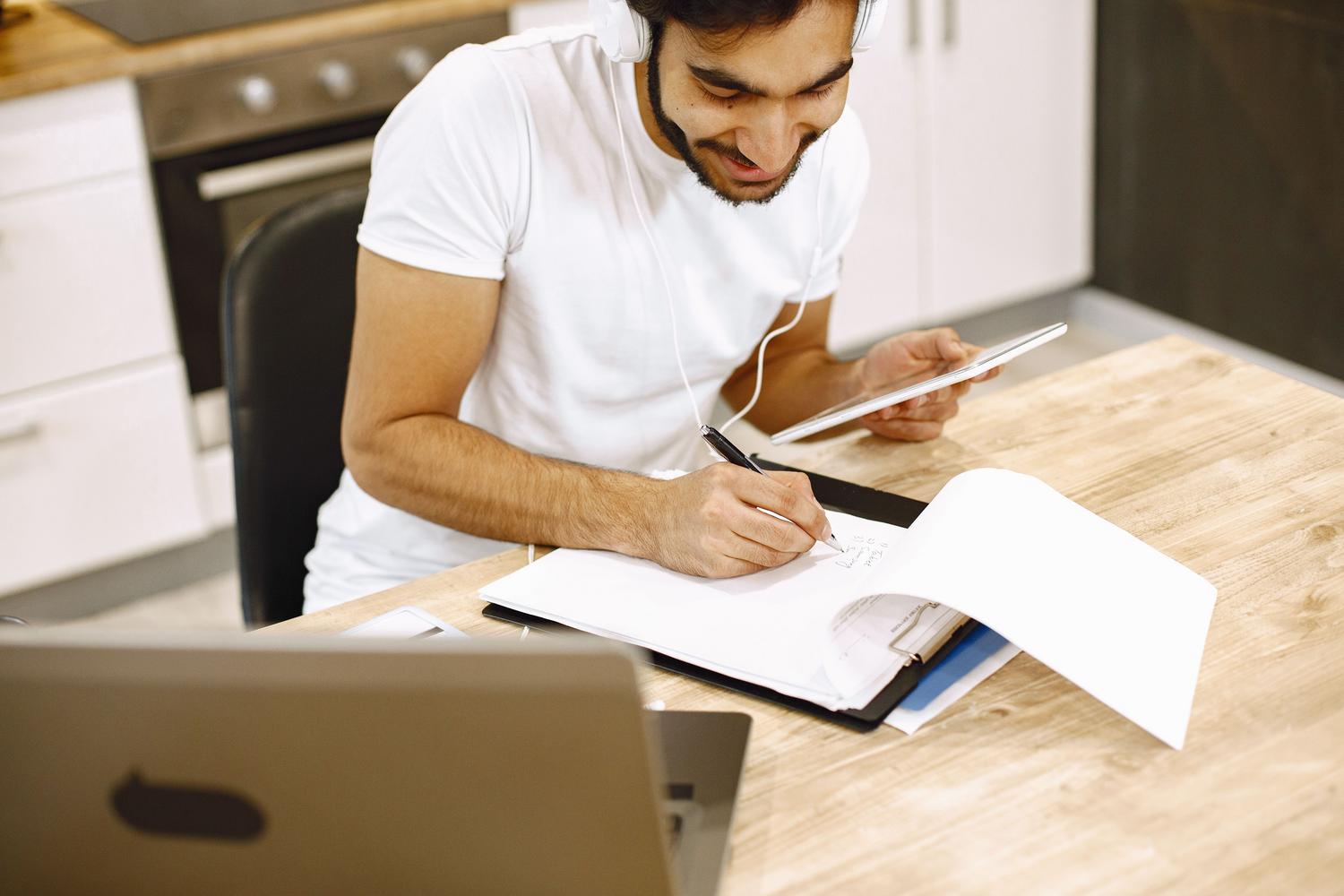 Persona utilizando simultáneamente una laptop, tablet y cuaderno físico, ilustrando el ecosistema multidispositivo de Microsoft 365.