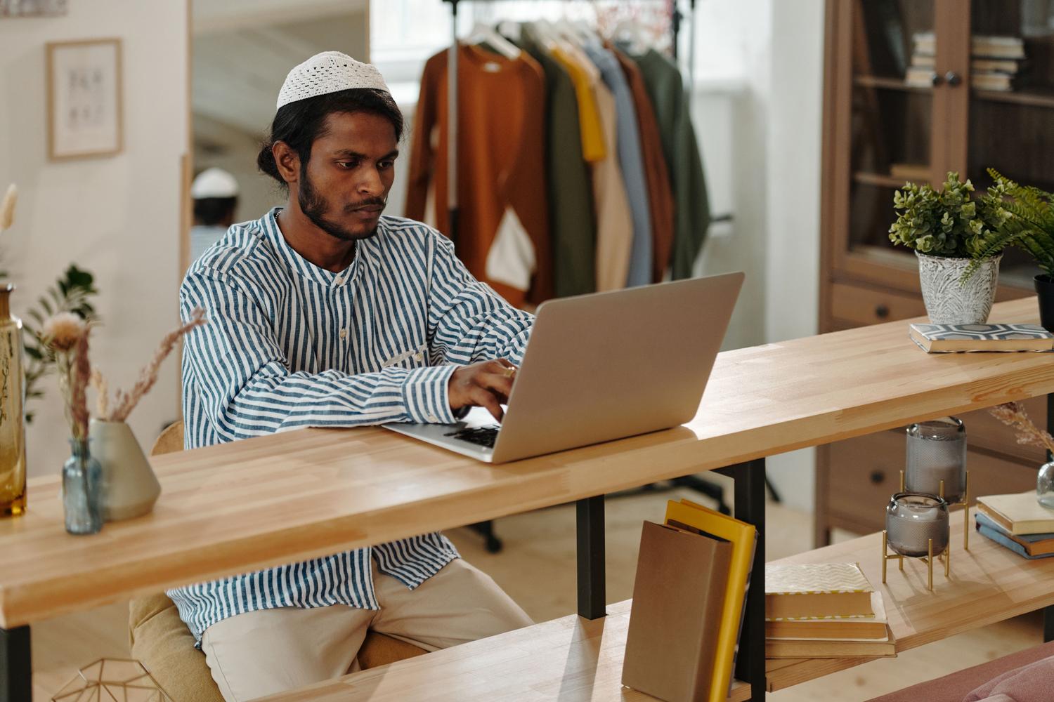 Hombre joven concentrado utilizando un ordenador portátil en un entorno de oficina moderno, representando al usuario siguiendo los pasos de configuración de sonido.
