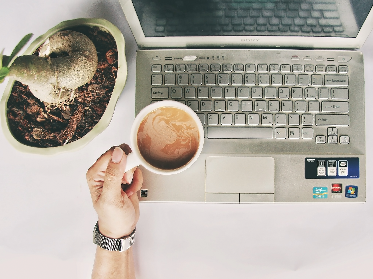 Espacio de trabajo acogedor en casa con un portátil y café, representando el trabajo remoto y relajado.