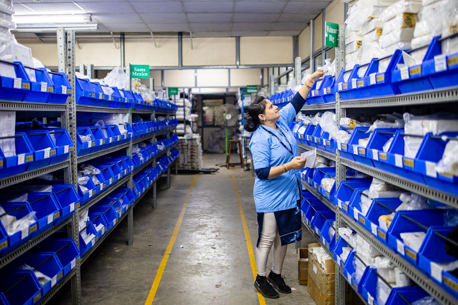 Trabajadora organizando el inventario en un pasillo de almacén, ilustrando el control de niveles de stock.