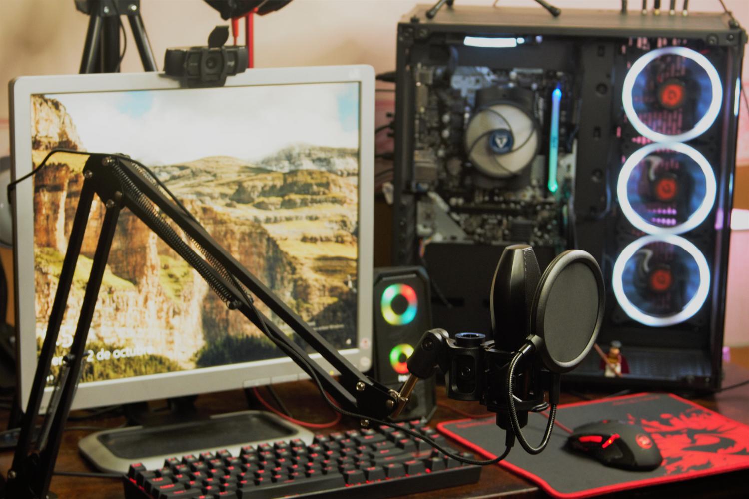 Professional gaming and recording setup featuring a microphone, monitor, and RGB-lit PC.