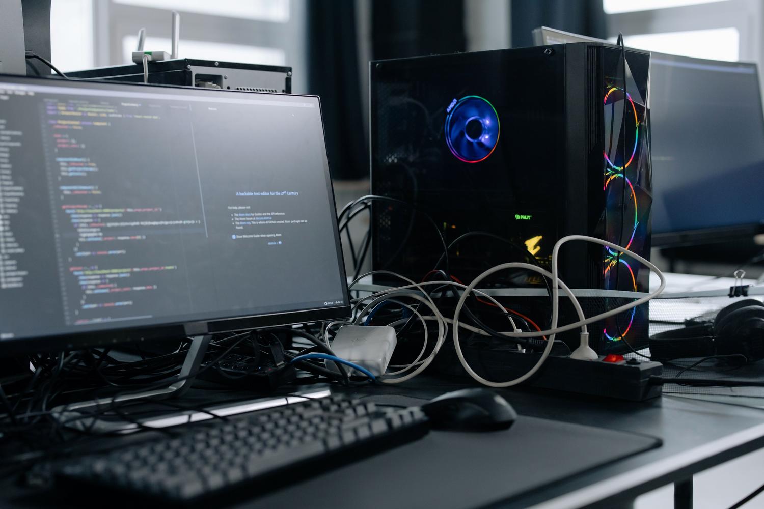 Estación de trabajo técnica con monitor mostrando código de programación y hardware de PC avanzado.
