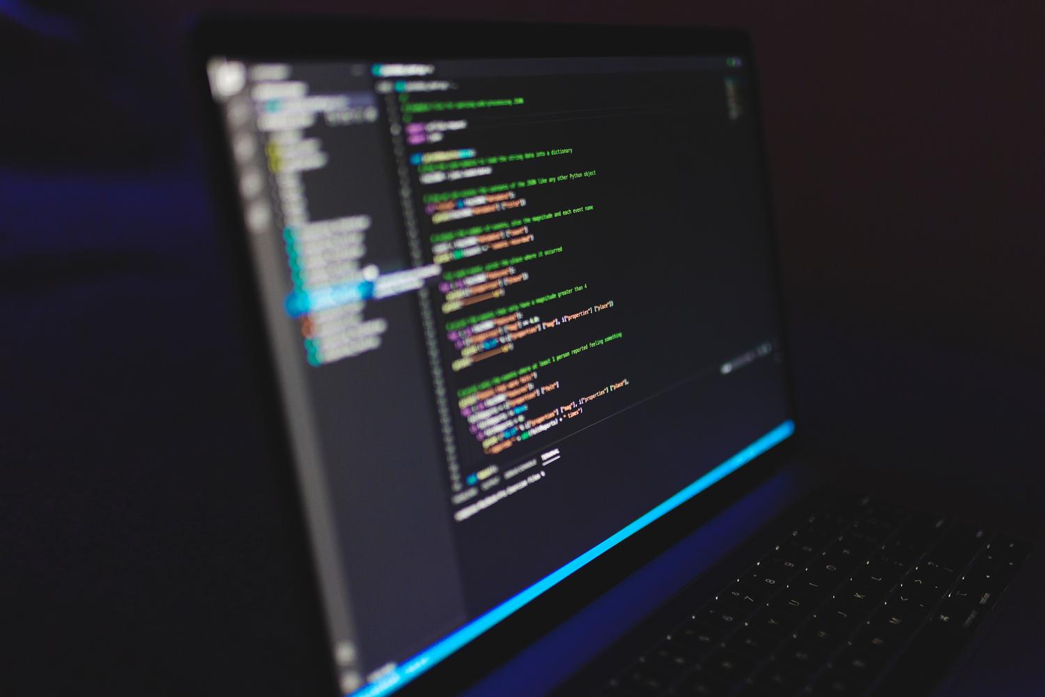 Pantalla de ordenador portátil mostrando líneas de código en un entorno de trabajo oscuro, destacando el ambiente de programación.