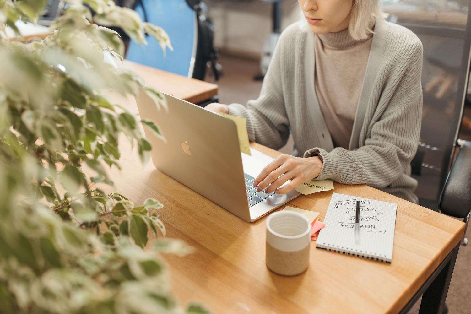 Una persona trabajando con un portátil en un escritorio de oficina en casa luminoso, representando la migración de correos corporativos a una cuenta personal de Gmail.