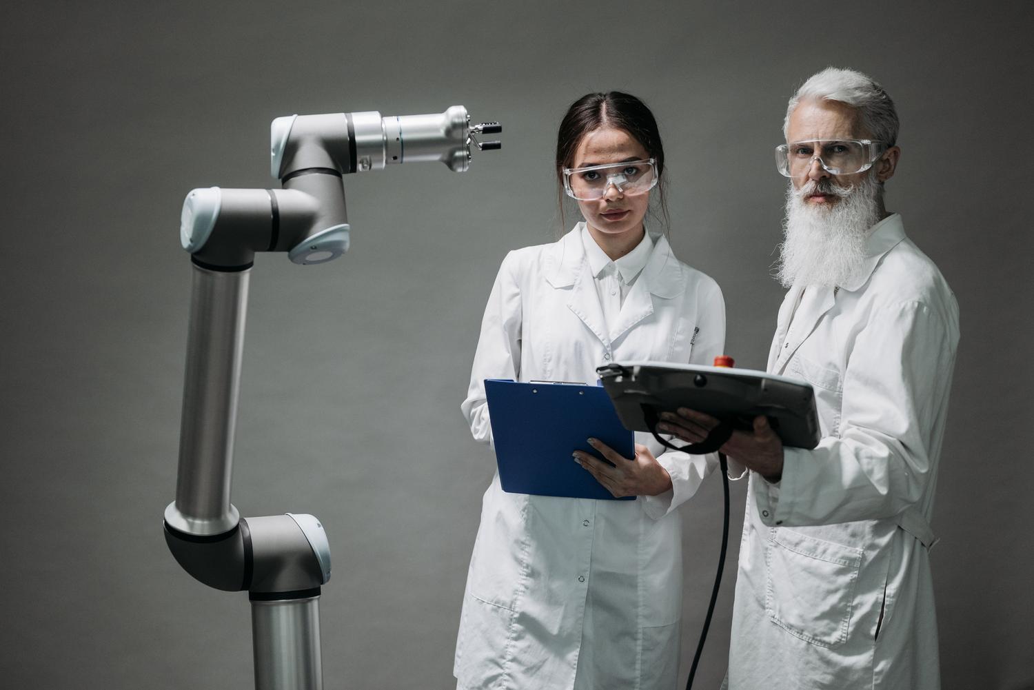 Expertos en robótica analizando la programación de un cobot mediante un controlador manual o teach pendant.