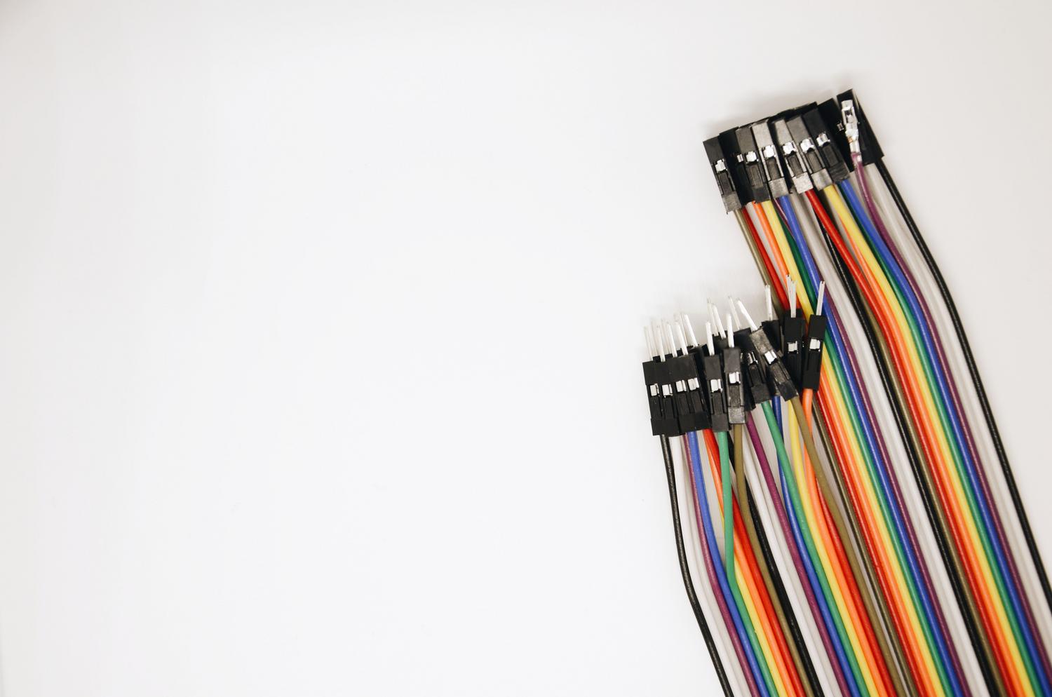 Set de cables jumpers de colores vivos sobre un fondo blanco, componentes esenciales para conectar sensores a Arduino.