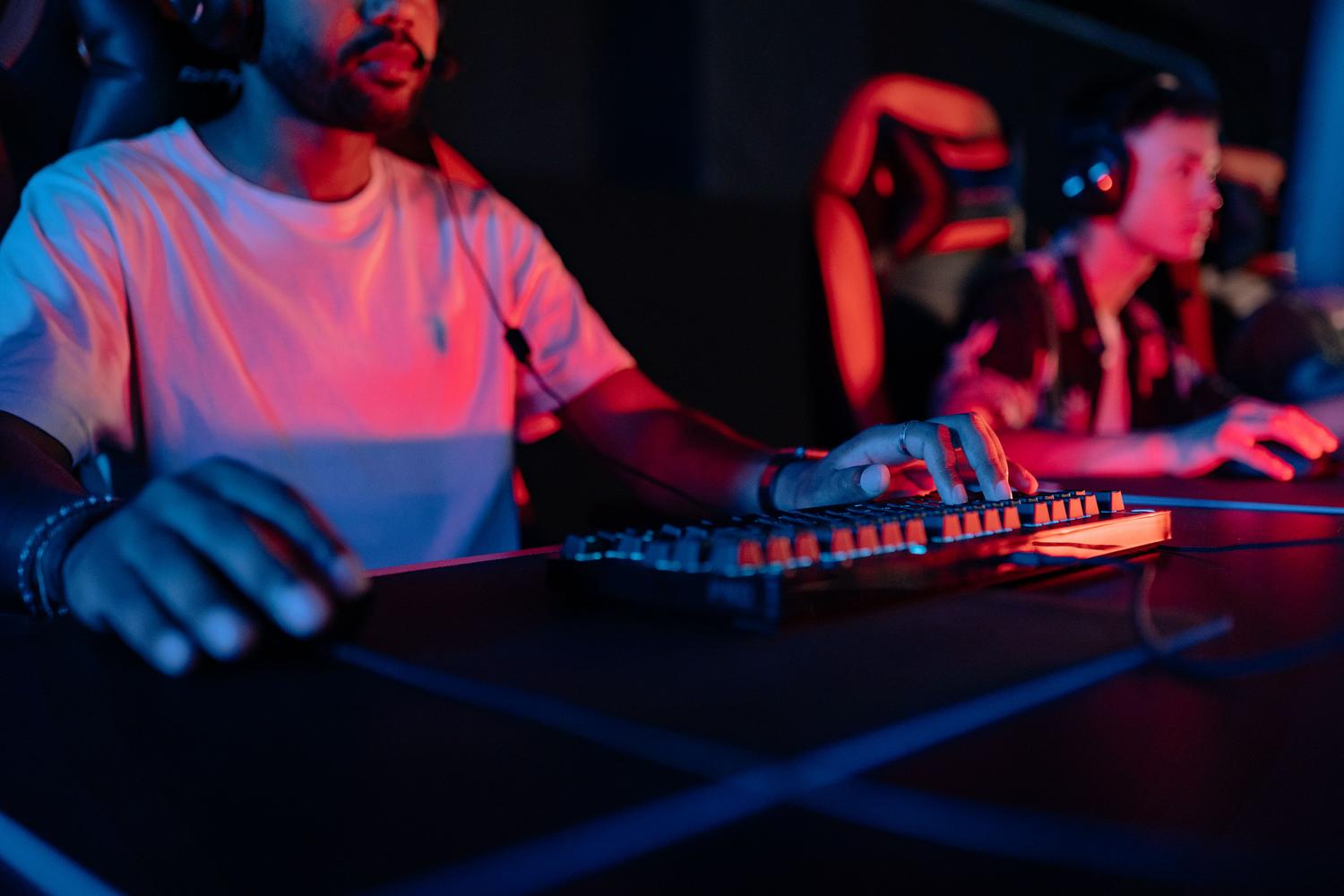 Jugadores concentrados en un setup gaming con iluminación neón, creando una atmósfera general de juego inmersivo.