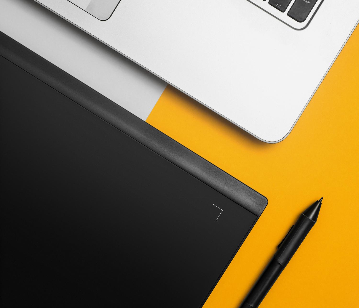 Espacio de trabajo creativo moderno con un ordenador portátil y una tableta digital sobre un escritorio colorido.