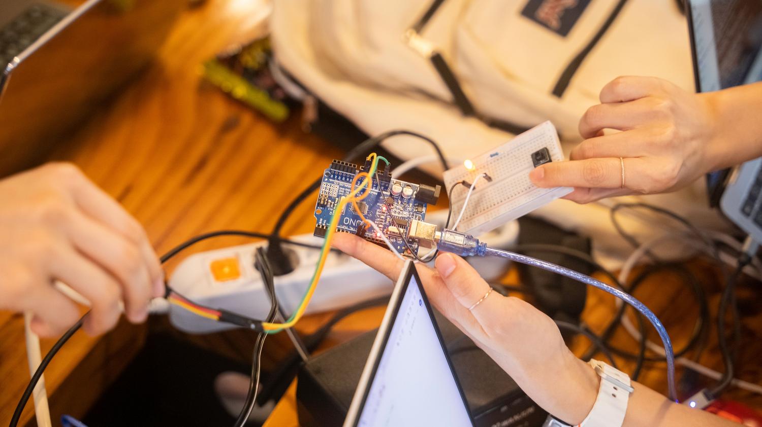 Estudiantes colaborando en el montaje de un circuito electrónico con Arduino y un ordenador portátil.