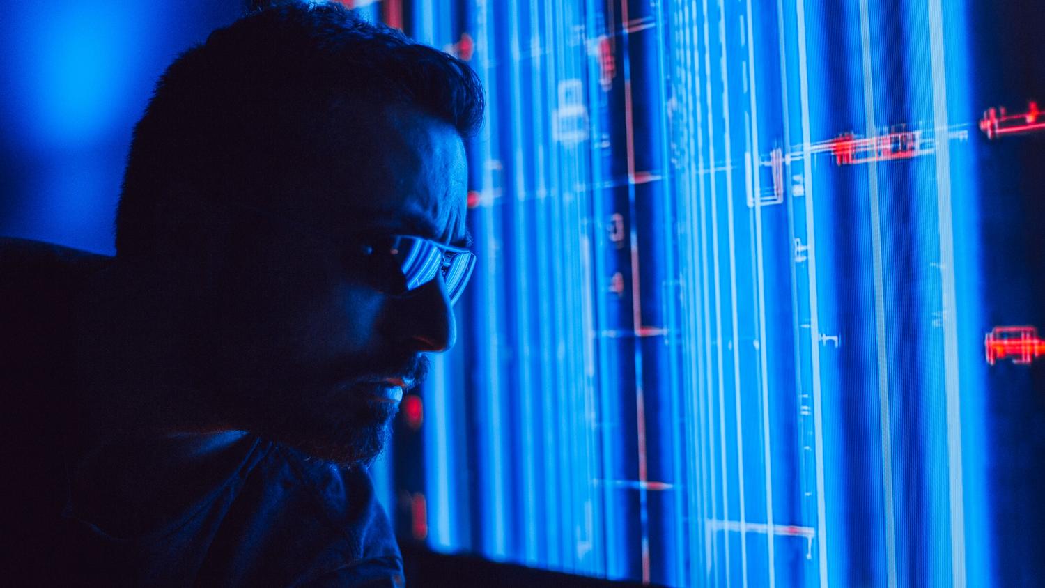 Hombre analizando una interfaz digital futurista con flujos de datos, representando el uso de inteligencia artificial como ChatGPT para la ciberseguridad.