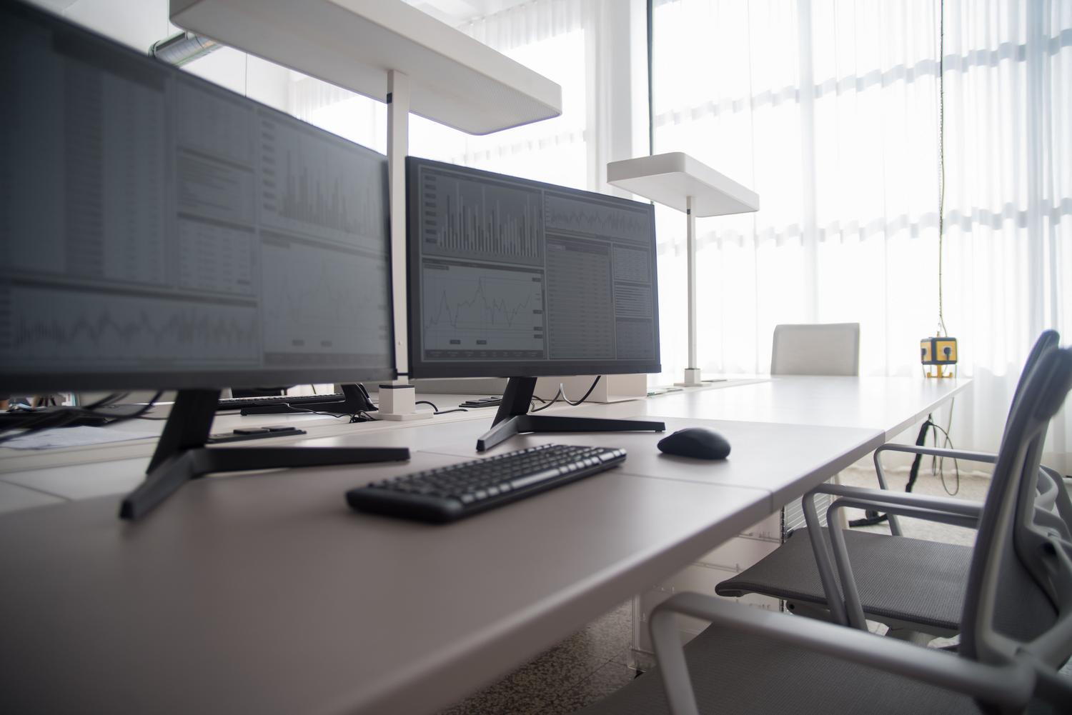 Espacio de trabajo profesional y organizado con múltiples monitores, reflejando la productividad y la gestión de datos.